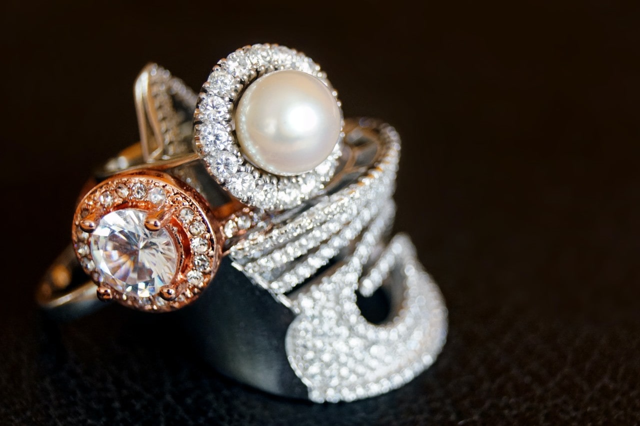 A close-up of multiple opulent gold rings, each adorned with sparkling diamonds. A close-up of multiple opulent gold rings, each adorned with sparkling diamonds.