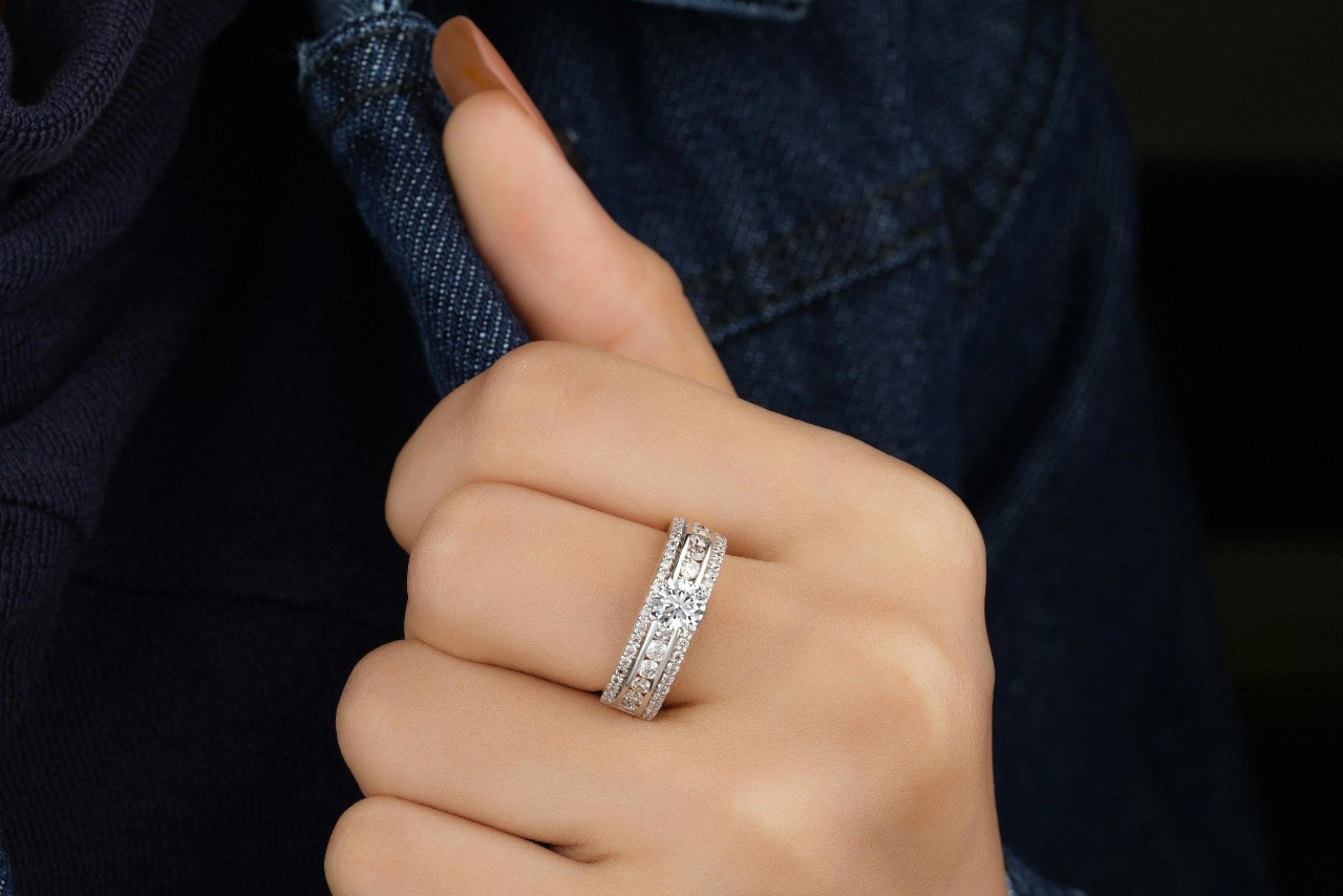 A close-up of a woman’s hand holding the front of her denim jacket, with emphasis on the dazzling white gold diamond ring on her finger. A close-up of a woman’s hand holding the front of her denim jacket, with emphasis on the dazzling white gold diamond ring on her finger.