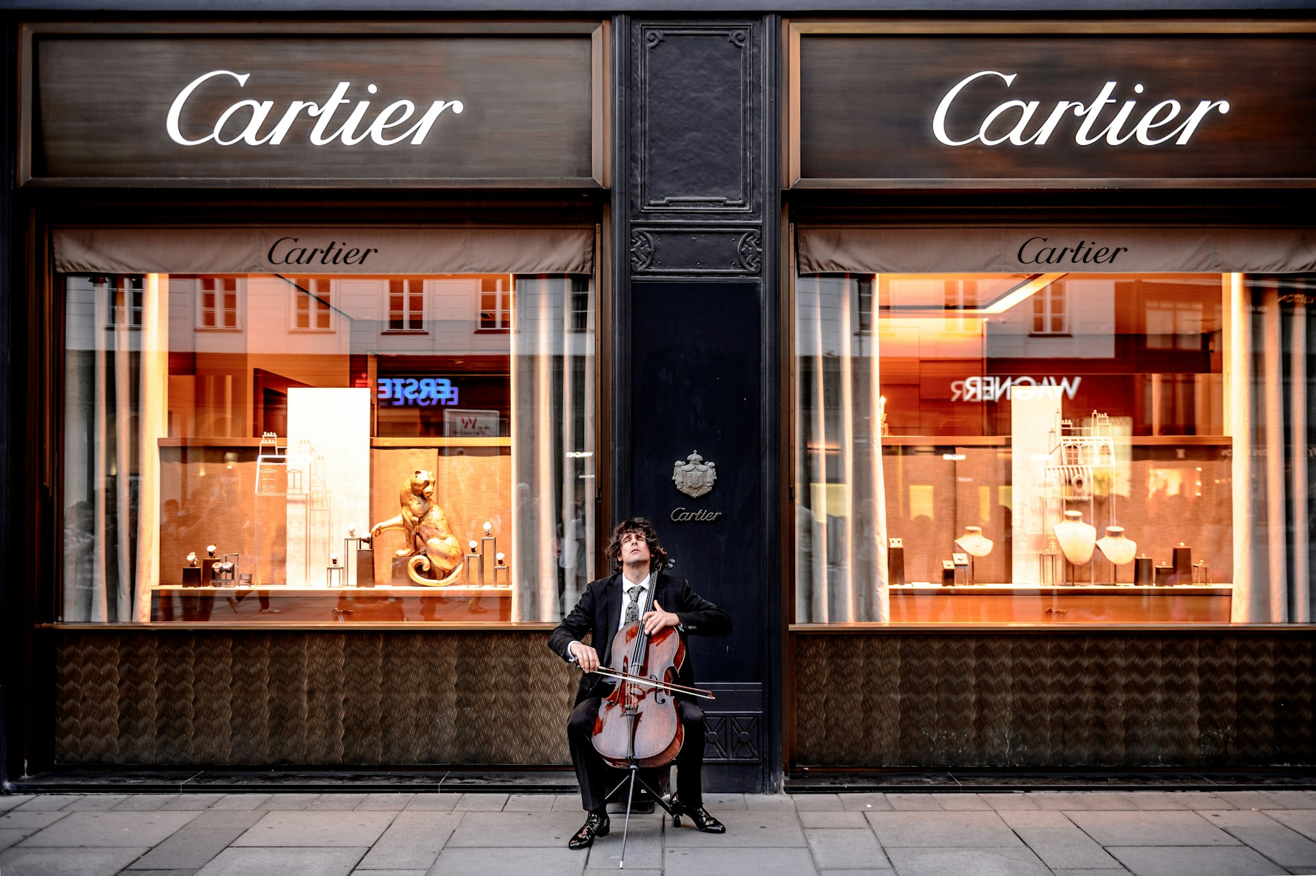 man with a cello sitting outside a Cartier store
