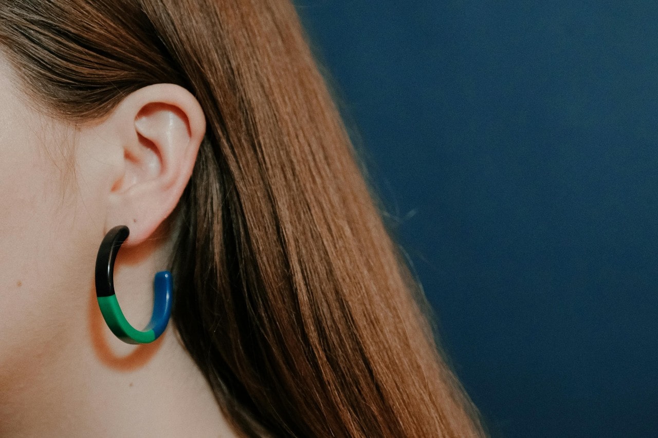 A close-up image of a woman wearing a color block hoop earring.