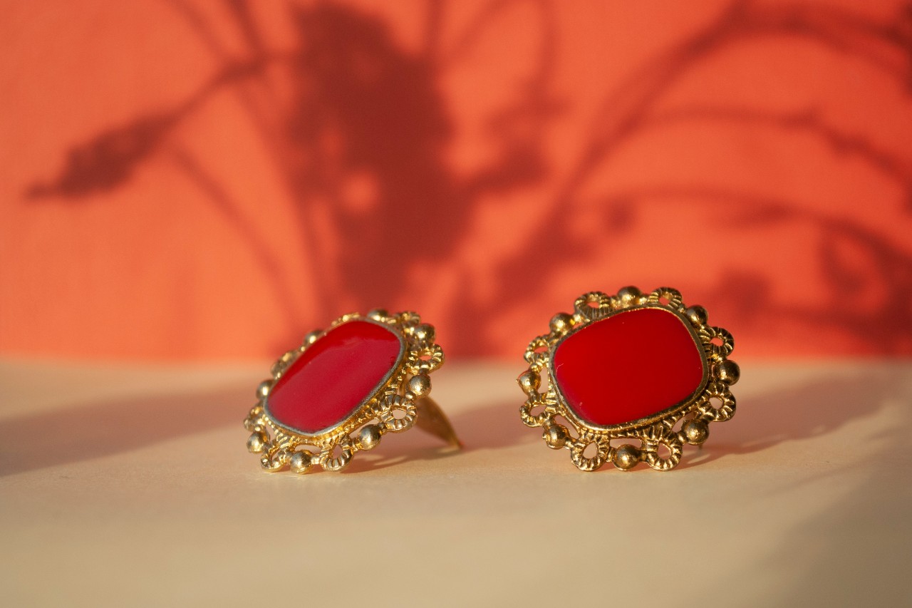 A pair of vintage-style red earrings with yellow gold details.