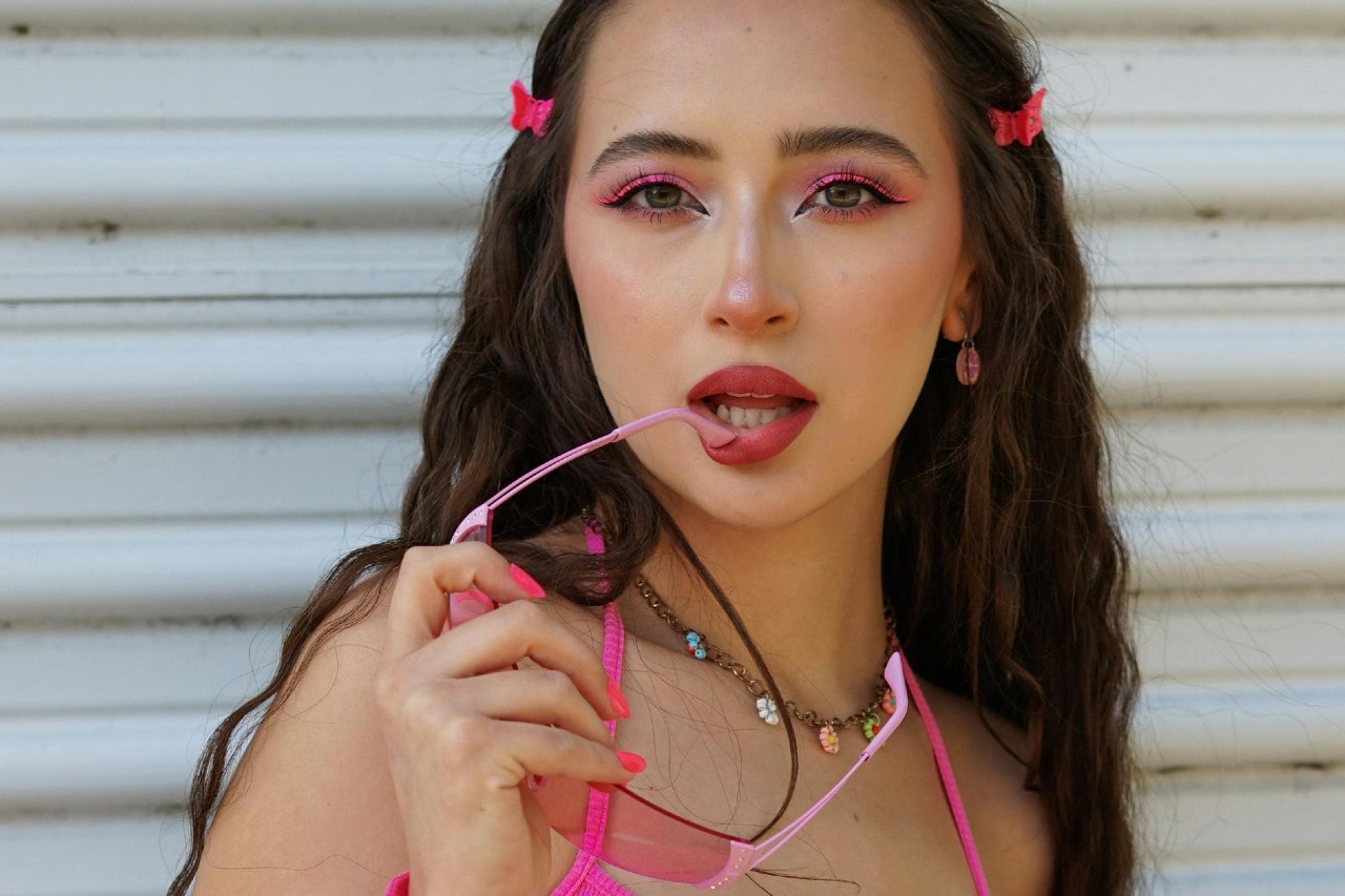 A young woman dressed in Y2K fashion, wearing a floral charm necklace.