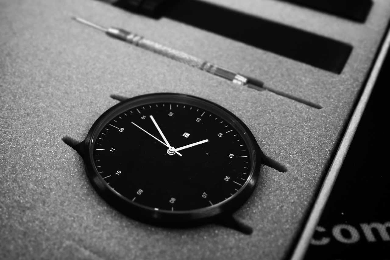 A black and white photo of a watch in pieces in a gift box.