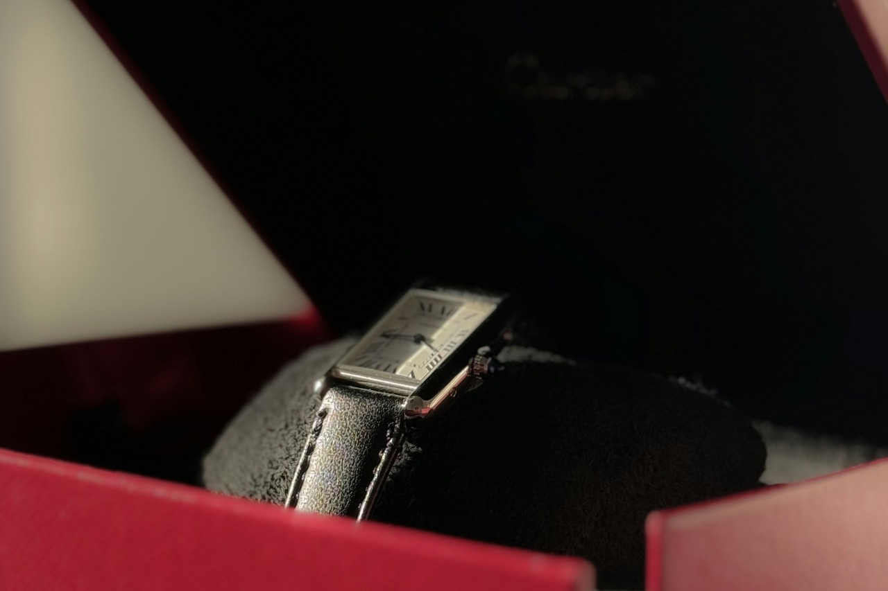 A close-up of a Cartier Tank watch in a red gift box.