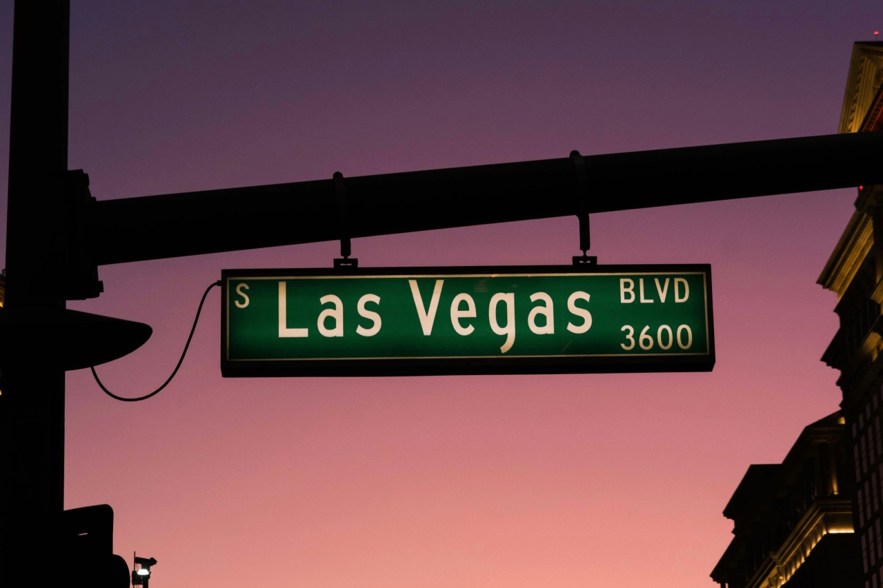 a “Las Vegas Blvd” street sign in front of a sunset sky