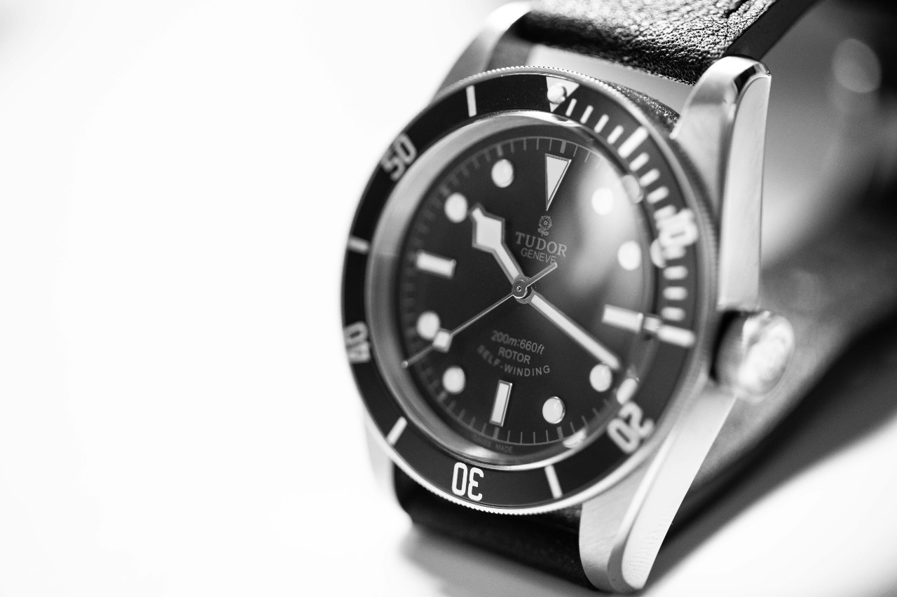 A close-up of a monochrome TUDOR Black Bay watch on a white backdrop.