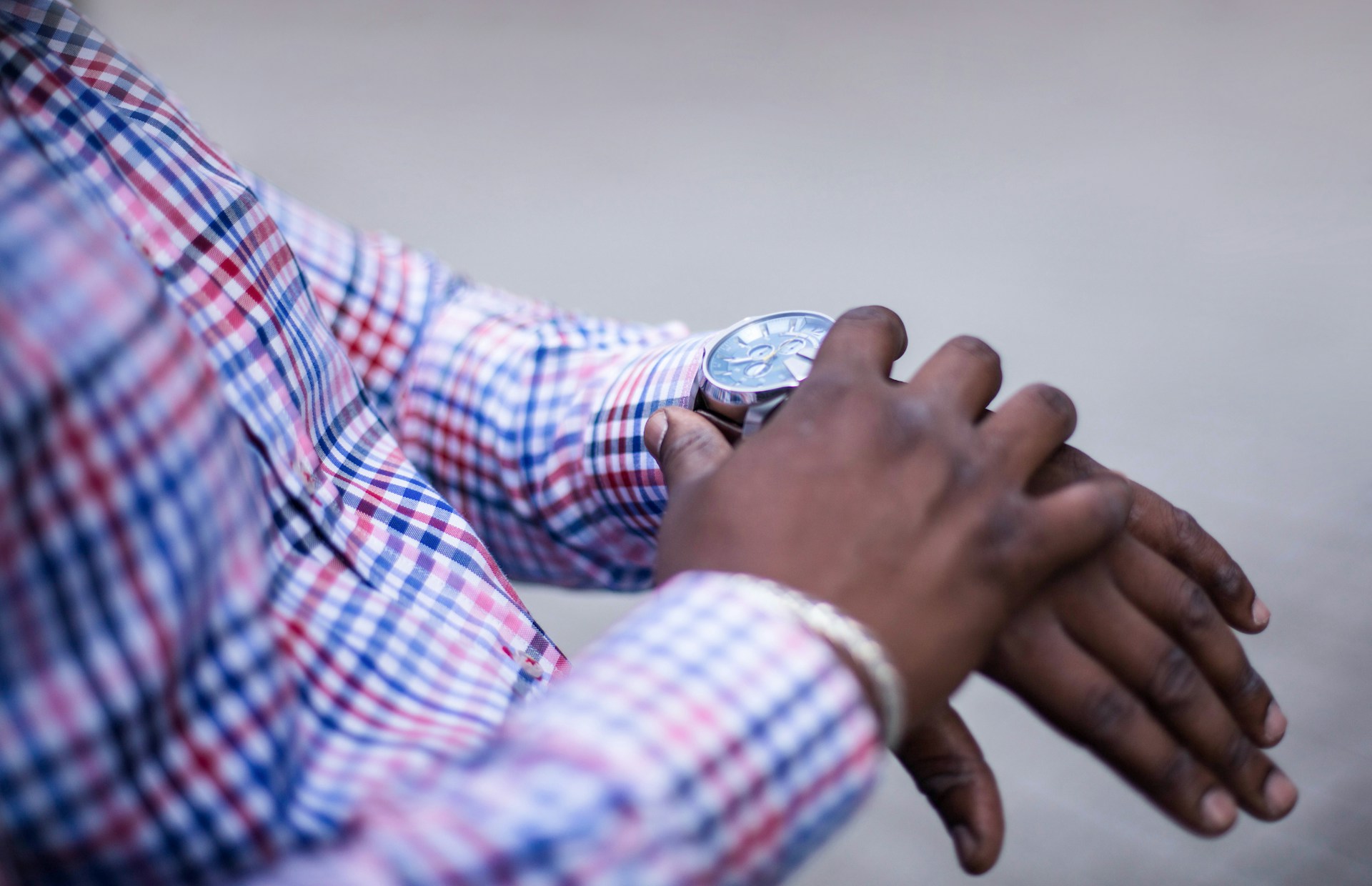 A man in a plaid shirt adjusting his fine timepiece.