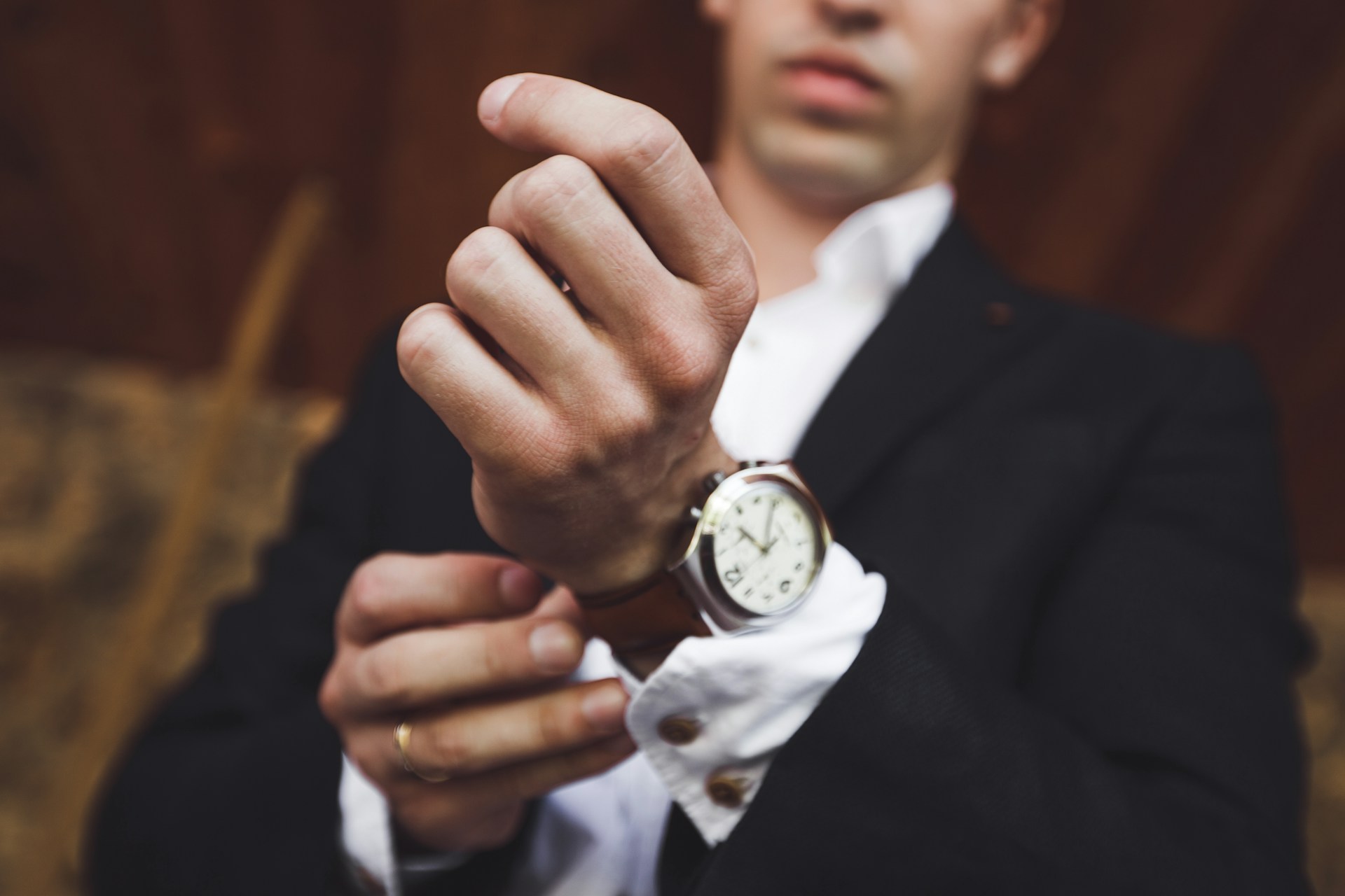 A well-dressed man adjusting the strap of his luxury watch.