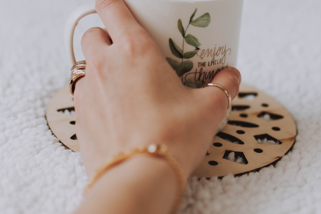 gold bracelet on hand holding mug