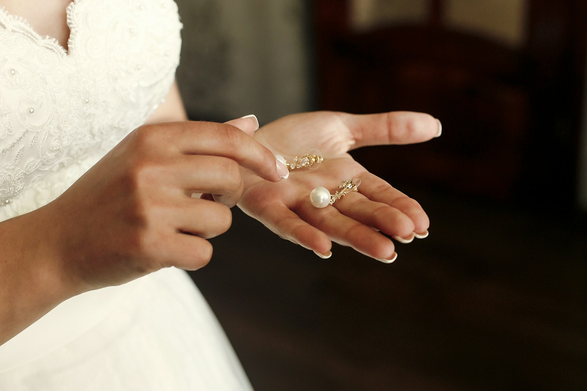 A close-up of a bride-to-be’s hand, with pearl earrings in her palm.