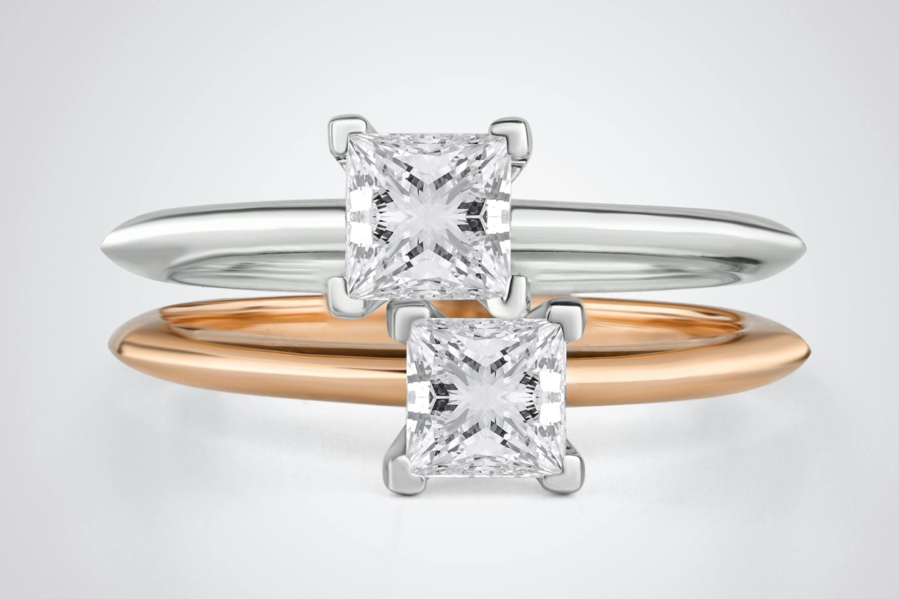 Two princess cut engagement rings in different rose and white gold, displayed one over the other.