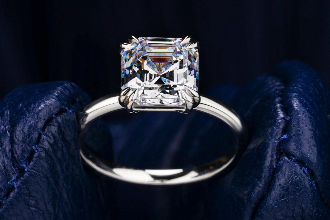 A close-up image of a solitaire engagement ring with an Asscher cut center stone.