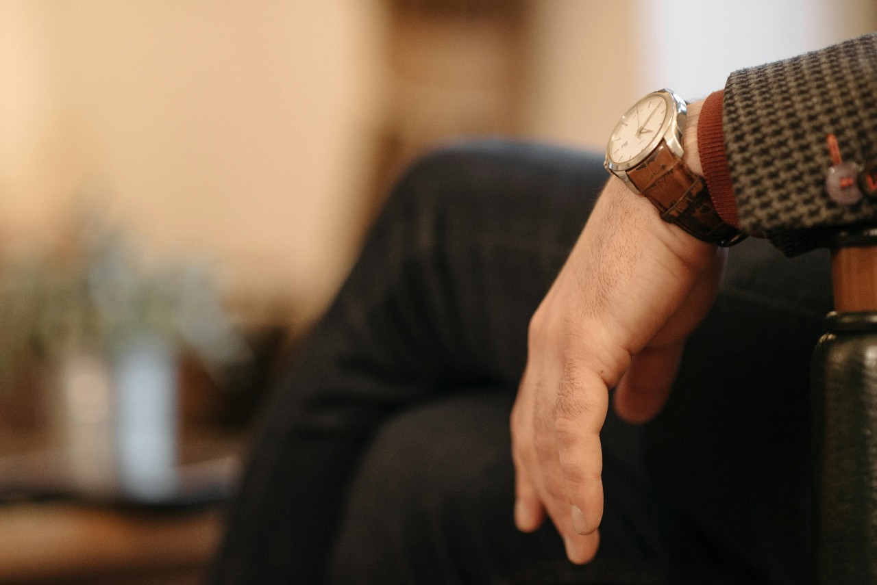 luxury watch on wrist of man sitting on chair