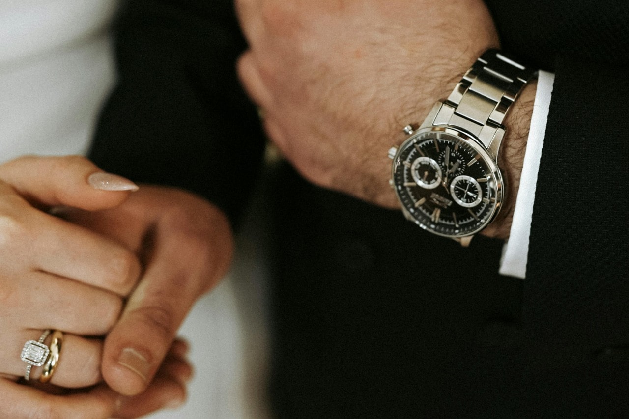 A close-up of a well-dressed man’s hands, adorned with a luxury watch.